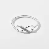 Anillo plateado con forma de infinito y pequeños cristales incrustados.