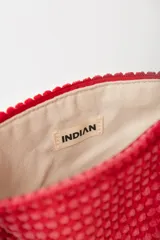 Neceser rojo con textura de tejido de toalla y cierre superior con cremallera.