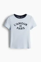 Remera celeste de punto acanalado con cuello redondo y ribete azul marino. Estampado frontal con la frase "L'amour Paris".