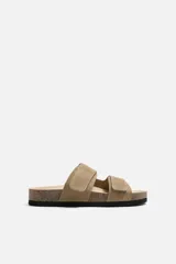 Sandalias color beige de piel con acabado serraje, doble tira con cierre adherente y plantilla anatómica.