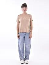 Remera blanca de algodón con cuello redondo y estampado frontal con la frase 'bloom with grace' en letras cursivas negras.