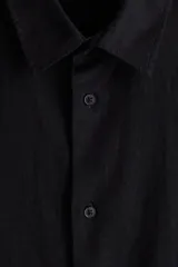 Camisa negra de manga corta en mezcla de lino y viscosa, con cuello inglés, tapeta lisa, canesú en la espalda y bajo recto. Corte holgado.
