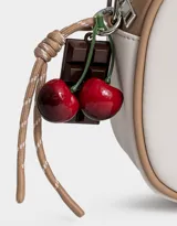 Bandolera de cuerina azul marino y beige con correa regulable azul y charm lateral decorativo. Tiene cierre superior y tag frontal con logo "The Brunch Club".