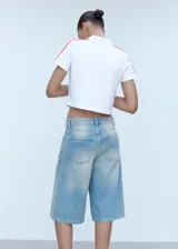 Polo deportivo azul con cuello clásico, corte entallado y mangas cortas con dos rayas blancas en los hombros.
