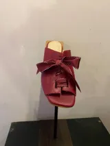 Sandalias negras de cuero sintético con tacón bloque y detalle de moños con pespuntes blancos en el empeine.