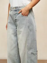 Jean ancho de tiro alto, color celeste claro desgastado, con corte holgado y bolsillos cargo en los laterales de las piernas.