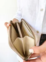 Billetera de cuero beige con cierre metálico, monedero interno y capacidad para billetes extendidos.