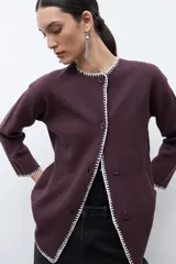 Saco de punto color ciruela oscuro, de manga larga y cuello redondo, con cierre frontal de botones y ribetes en contraste blanco con puntada decorativa.