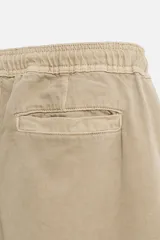Bermuda color beige de denim de algodón, corte relaxed fit, con cintura elástica ajustable con cordón, bolsillos frontales y traseros.