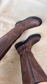 Botas de caña alta color beige y puntera marrón, con suela track y detalle de estrella blanca en el lateral.