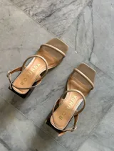 Sandalias de cuero color beige con dos tiras finas en el empeine, tira al tobillo con hebilla y tacón cuadrado de madera.