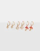 Set de tres pares de aros tipo argolla bañados en oro, con dijes colgantes: corazón, trébol de cuatro hojas y hongo.