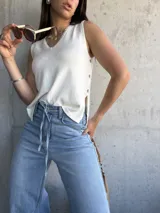 Musculosa tejida color crema con escote en V y botones laterales.