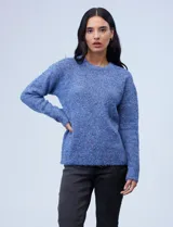 Buzo de tejido melange color beige con puntos oscuros, cuello redondo y manga larga.