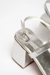 Sandalias plateadas de cuero vacuno, con dos tiras horizontales en el empeine y tobillo, ajuste con hebilla, plataforma delantera y tacón cuadrado.