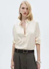 Camisa color crema de manga larga con puños abotonados y cuello camisero.