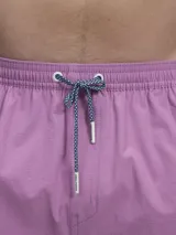 Short de baño verde con estampado de margaritas blancas y cordón ajustable naranja.