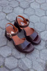 Sandalias de cuero color chocolate con plataforma y tacón cuadrado. Tira ancha sobre los dedos y tira con hebilla al tobillo.