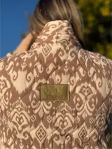Chaqueta acolchada con estampado ikat en tonos beige y marrón, de corte holgado y cuello mao.
