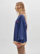 Buzo negro de corte oversize, confeccionado en algodón, con detalles en las mangas y el cuello.