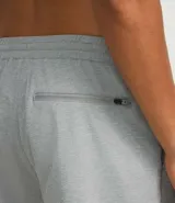 Bermuda deportiva gris de poliéster con cintura elástica y cordón interno ajustable. Cuenta con un bolsillo trasero funcional con cierre de cremallera.