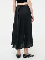 Falda larga color blanco, confeccionada en lino, con corte cruzado y abertura frontal. Presenta pretina ancha con lazo de ajuste en cuero sintético.