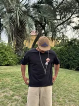 Remera de algodón negra con estampado de un balón de fútbol americano y la frase "Together, we are America". Incluye una firma en blanco debajo del balón.