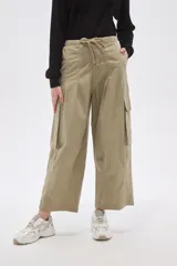 Pantalón cargo de algodón color verde oliva, tiro bajo, con cintura ajustable mediante cordón y piernas anchas y rectas. Presenta bolsillos cargo en los laterales.