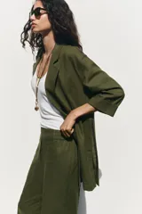 Pantalón color beige de lino, de tiro alto con cintura elástica, bolsillos laterales ocultos en costura y pernera ancha.