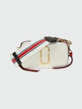 Bandolera Marc Jacobs modelo The Snapshot, de cuero color gris con detalles en beige y herrajes dorados. Presenta correa de tela con el logo de la marca y doble compartimento con cierre.