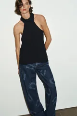 Top negro con cuello halter ajustable con lazada y hombros descubiertos. Presenta cierre lateral con cremallera oculta.