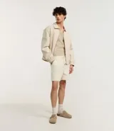 Bermuda deportiva de terciopelo color crema, con cintura elástica ajustable con cordón y bolsillos laterales.