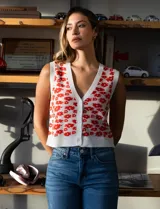 Chaleco tejido blanco con estampado floral rojo, escote en V y cierre frontal con botones.