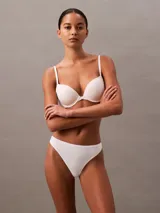 Conjunto de ropa interior Calvin Klein color blanco, compuesto por un corpiño con aro y breteles regulables, y una bombacha colaless de microfibra con cintura elástica.