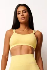 Top deportivo amarillo con textura acanalada, tecnología seamless, breteles finos cruzados en la espalda y abertura interna para copa.