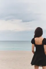 Vestido corto negro de popelín con escote cuadrado, mangas cortas abullonadas, bolsillos laterales ocultos y detalle de encaje a tono.