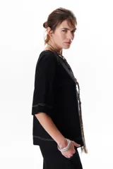 Blusa de lino color beige claro, con mangas 3/4 y cuello redondo. Presenta pespuntes a contratono en el centro, puños y ruedo.