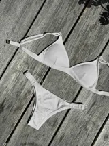 Conjunto de bikini turquesa con corpiño triangular de corte fijo, breteles regulables y almohadillas desmontables, y bombacha vedetina con frunce elástico en los costados.