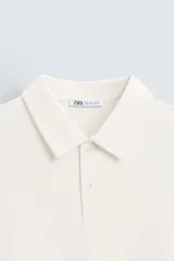 Polo de piqué color crudo, corte regular fit, cuello solapa con cierre de botonadura y mangas cortas.