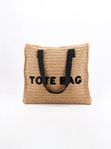 Bolso tote de color beige trenzado con asas negras y el texto 'TOTE BAG' en la parte frontal.