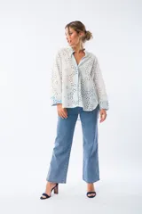 Camisa blanca con broderie y mangas largas con puños en color azul.