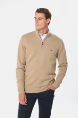 Buzo tejido de lana color beige, con medio cierre metálico y cuello alto. Tiene un pequeño logo bordado en el pecho.