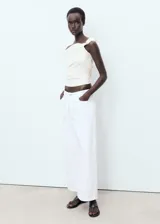 Top entallado color crema, sin mangas, con diseño asimétrico de palabra de honor y fruncido lateral.