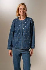 Campera de jean azul con manga larga, corte holgado, cuello redondo y cierre frontal con botones. Presenta bolsillos delanteros y detalles de ojales metálicos.