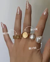 Set de tres anillos dorados: uno con eslabones tipo cadena, uno con forma de sello circular y uno con una perla irregular.