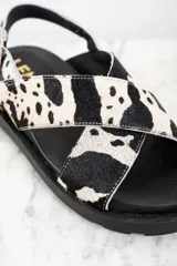 Sandalias con tiras cruzadas de cuero con estampado animal print de vaca en blanco y negro.