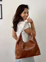 Cartera marrón de cuero genuino, con costuras a la vista y correa de hombro.