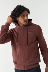 Campera de felpa color ladrillo con capucha ajustable, cierre frontal y bolsillos laterales con cierre. Tiene puños y logo bordado en la espalda.