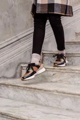 Championes de cuero color marrón, negro y beige, con cordones negros y suela blanca.