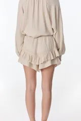 Short pollera blanco de tela arrugada con volados y detalles de encaje.